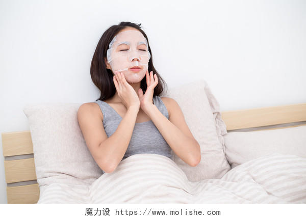 亚洲的年轻女人在床上敷面膜面部清洁脸部面部补水